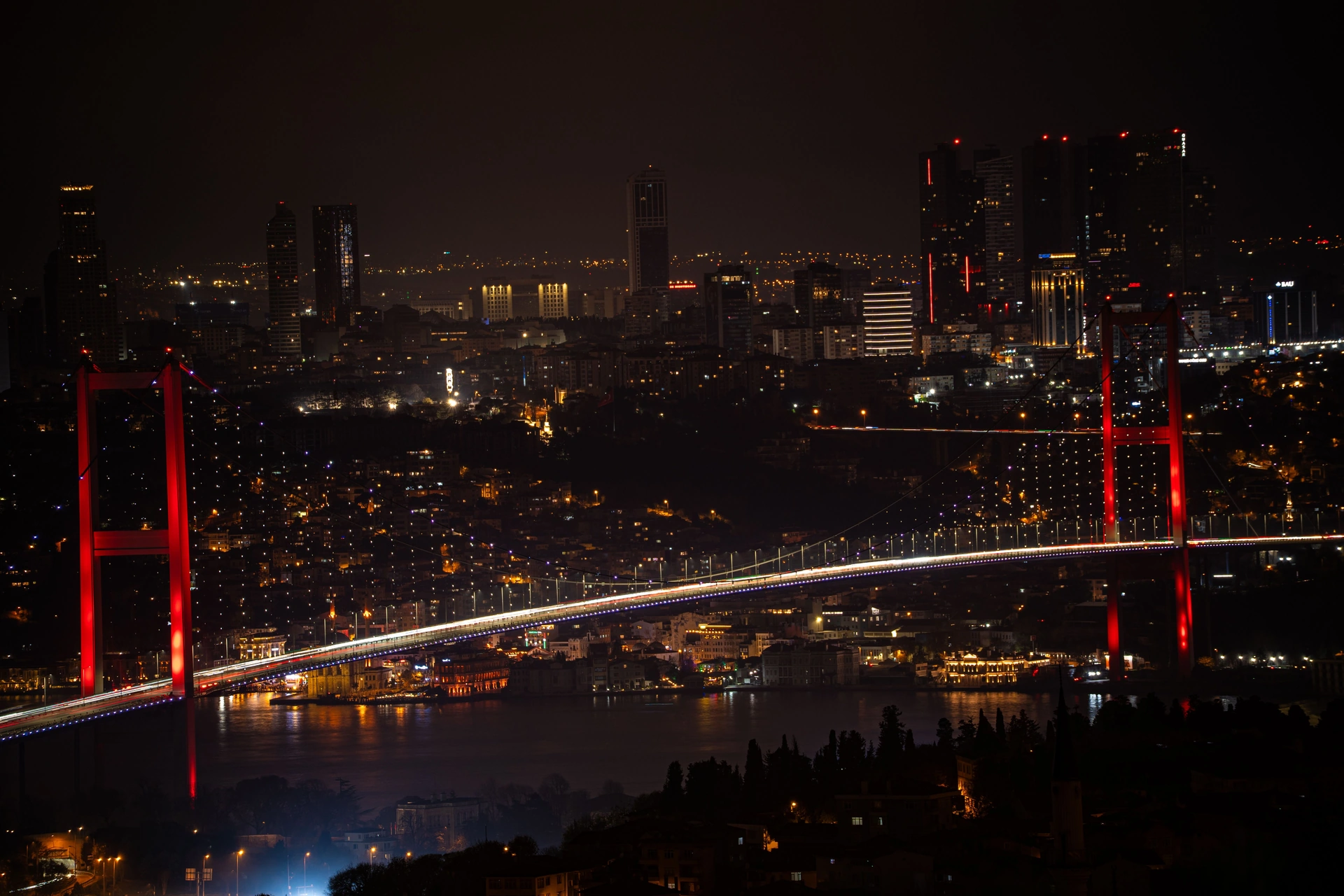 The illuminated Bosphorus Bridge and Istanbul skyline at night.